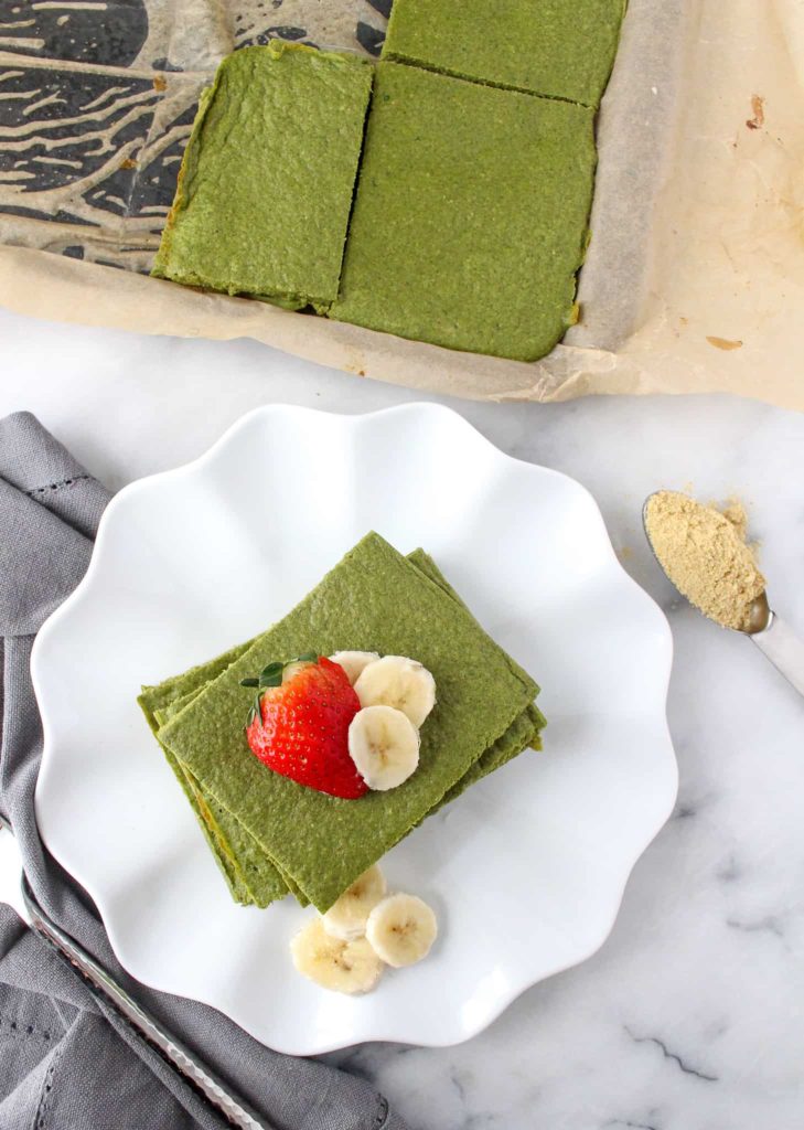Stack of green pancakes with strawberries and bananas